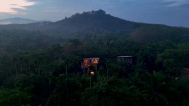 Canlı orman yapraklarının arasında, uzak Tayland 'da eşsiz bir mimari ağaç evi bekliyor. Sakin atmosfer, hava karardıkça doğanın güzelliğini arttırıyor. Yapıları yeşillikle harmanlıyor..