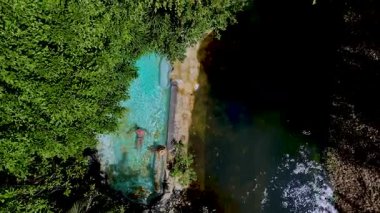 Yüzücüler canlı yeşillik ve tropikal ağaçlarla çevrili sakin bir doğal havuzun ferahlatıcı sularının tadını çıkarırlar. Tayland 'daki doğal havuzun insansız hava aracı görüntüsü