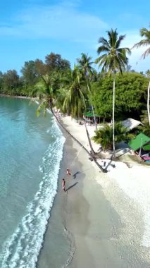 İki insan, sallanan palmiye ağaçları ve kristal berrak sularla çevrili Koh Kood Adası Tayland 'ın el değmemiş sahillerindeki sakin atmosferin tadını çıkarıyor. Dinlenme ve rahatlama için mükemmel..