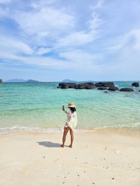 Tayland 'daki Koh Kham Adası' nda sakin bir anı yakalayan bu kumsala giden sıcak güneşin ve yumuşak dalgaların tadını çıkarıyor. Kristal berrak sular ve yumuşak kumlar mükemmel bir tropikal cennet yaratıyor..