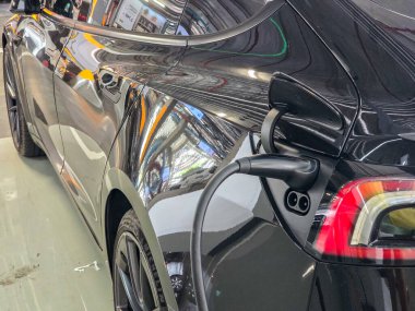 Çevre dostu seyahat meraklıları için mükemmel bir mekanda çalışan siyah elektrikli bir araç. EV araba şarj oluyor