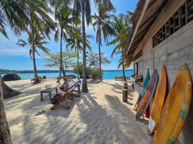 Tayland, Koh Kham 'ın dingin güzelliğini görün. Kum kıyıları, sallanan palmiye ağaçları ve renkli sörf tahtaları mükemmel bir tropikal kaçış sağlar. Huzurlu ortamın ve hareketli çevrenin tadını çıkar..