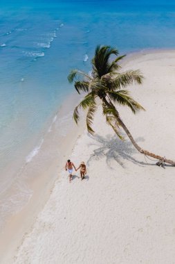 Romantik bir çift, Tayland 'ın Koh Kood Adası' nın turkuaz suları ve sallanan palmiyelerle çevrili güzel bir an yaratmak için el ele yürür.