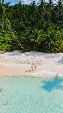 Bir hava görüntüsü, Koh Kood Adası Tayland 'ın güzel sahillerinde, palmiye ağaçları ve berrak suların ortasında, bir kaçış için mükemmel bir romantik zemin oluşturan, el ele yürüyen bir çifti gösteriyor.