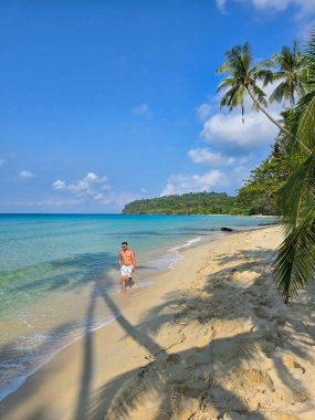 Bir gezgin, Tayland 'ın Koh Kood Adası' nın altın kumlarında yürüyor. Durgun turkuaz suların ve sallanan palmiyelerin tadını çıkarıyor. Huzurlu bir tropikal kaçış yaratıyor..
