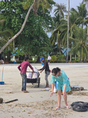Koh Kood, Tayland, 13 Mart 2025, yerel halk plaj temizliği yapıyor, çöpleri ve enkazı temizliyor. Güneşli günde hindistan cevizi palmiyeleri ve canlı yeşillikler sergileniyor, adanın doğal güzelliğini vurguluyor..