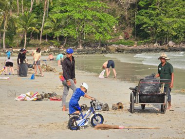 Koh Kood, Tayland, 13 Mart 2025, Topluluk üyeleri plajı temizlemek ve çevre bilincini artırmak için toplandılar. Fırtınadan sonra plajı temizleyen bir turist.