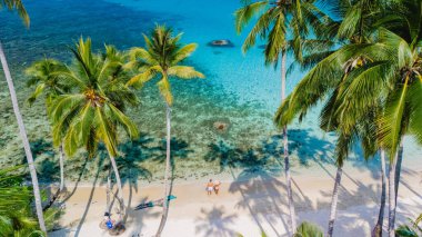 Bir hava fotoğrafında Tayland 'ın Koh Kood Adası' ndaki el değmemiş bir plajın güzelliği, yüksek palmiye ağaçları ve dinginlik ve huzur için ideal turkuaz sularla gözler önüne seriliyor.