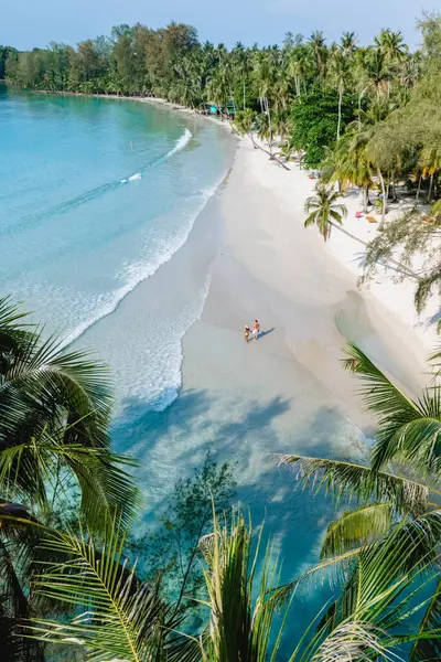 Ziyaretçiler Tayland 'daki Koh Kood Adası' nın el değmemiş kıyı şeridi boyunca yürürken, sallanan palmiye ağaçları altında sallanan beyaz kumların ve nazik dalgaların dinginliğini kucaklıyorlar..