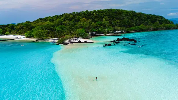Kristal berrak turkuaz sular Koh Kham Adası 'nın kumlu kıyılarını öpüyor ve tropik bir cennet sergiliyor. Yeşillik ve kayalık oluşumlar Tayland 'ın kıyı güzelliğini arttırır.