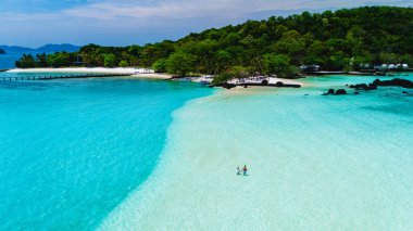 Nefes kesici turkuaz sular Tayland 'daki Koh Kham Adası' nda yumuşak kumlu plajlarla buluşur. Ziyaretçiler dingin ortamın tadını çıkarırlar. Doğal güzellikleri keşfetmek ve rahatlamak için mükemmeldirler..