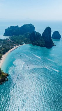 Parlak turkuaz sular, dramatik kireçtaşı kayalıklarıyla çevrili Railay Sahili kıyılarını kucaklıyor. Tekneler denizde süzülüyor, Krabi Tayland 'ın dingin güzellikleri arasında maceraya davetiye çıkarıyor..