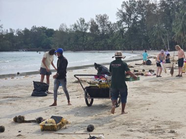 Koh Kood, Tayland, 13 Mart 2025. Gönüllüler ve yerliler sahili temizlemek için sahilde toplanıyor. Kumdan enkazı temizliyorlar..