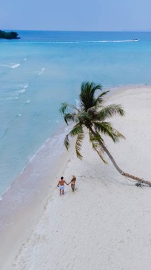 Bir çift, Tayland 'daki güzel Koh Kood Adası' ndaki çarpıcı beyaz kumların üzerinde el ele yürüyor ve tropik cennet kaçamağının özünü mükemmel bir şekilde yakalıyorlar.