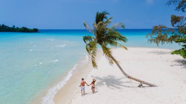 Tayland 'ın Koh Kood plajında el ele gezen bir çift turkuvaz suları ve sallanan palmiye ağaçları arasında mahremiyet ve sükunetle dolu romantik bir kaçamağın tadını çıkarıyordu.