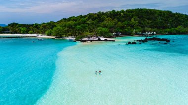 Turkuvaz suları ve yemyeşil yeşilliklerle çevrili Koh Kham Adası Tayland 'ın yumuşak kıyı şeridi boyunca yürüyen iki eğlence düşkünü. Huzurlu ortam rahatlamayı ve macerayı davet eder..