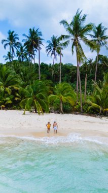 Tayland 'daki Koh Kood Adası' nda iki insan dingin, berrak suların ve hafif esintide sallanan canlı palmiyelerin tadını çıkararak nefes kesici bir kumsal manzarası yaratıyor.