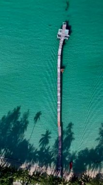 Koh Kood Tayland 'daki berrak sulara uzanan nefes kesici bir iskelede sakin anlar yaşayın. Sahne, dalgalı palmiyeler ve gevşemek için mükemmel mavi okyanuslar tarafından çerçevelenmiştir..