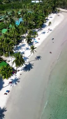 Yumuşak beyaz kumların berrak sularla buluştuğu Koh Kood Adası Tayland 'ın sakin kıyılarını keşfedin. Sahile gidenler sallanan palmiye ağaçlarının altında dinleniyor, parlak bir gökyüzünün altında huzurlu atmosferin tadını çıkarıyorlar.