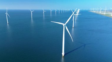 Açıklardaki rüzgar türbinleri açık mavi gökyüzüne karşı dik durarak Kuzey Denizi 'nde yenilenebilir enerji üretiyor. Bu etkileyici yel değirmeni parkı Hollanda 'daki sürdürülebilir enerjinin geleceğini somutlaştırıyor..