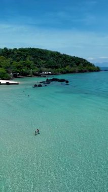 Turkuaz sular Koh Mak ve Koh Kham Tayland 'ın altın kumları üzerinde tur atar ve ziyaretçileri bu tropik cennette dinlenmeye ve yüzmeye davet eder. Bereketli yeşillik adaların dingin güzelliğini artırır..