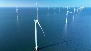 Hollanda 'da, yenilenebilir enerji kullanan çok sayıda yüksek rüzgar türbininin bulunduğu çarpıcı bir yel değirmeni parkını deneyin. Açık mavi gökyüzü ve sakin sular sakin bir atmosfer yaratır..