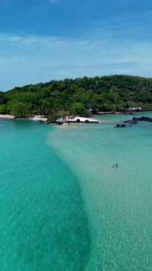 Koh Mak ve Koh Kham Adası 'ndaki berrak turkuaz suların ve tozlu beyaz kumların nefes kesici manzarası. Güneşlenenler, yüzücüler ve doğa severler yemyeşil sularla çevrili huzurlu atmosferin tadını çıkarırlar..