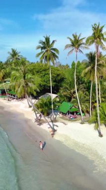Tayland 'daki Koh Kood Adası' nın güzelliğini keşfedin. Altın kumların gök mavisi sularla buluştuğu yer. Palmiye ağaçları, ziyaretçiler sakin kıyı şeridinde yürürken usulca sallanıyor..