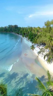 Bereketli palmiye ağaçları ve Koh Kood Adası 'ndaki berrak mavi sularla çevrili sakin bir sahilin çarpıcı manzarası. Ziyaretçiler doğada güneşin altında sükunetin tadını çıkararak Tayland 'da mükemmel bir kaçış yaratıyorlar.