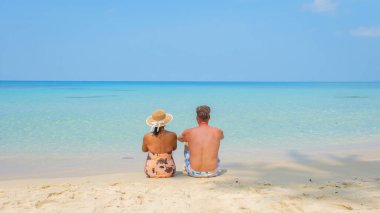 Tayland 'daki Koh Kood Adası' nda, sevgi dolu bir çift kumsalda huzurlu bir anın tadını çıkarıyor, turkuaz suların dinginliğini kucaklıyor ve günlük sıkıntılarını geride bırakıyorlar.