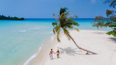 Tayland 'ın Koh Kood Adası' nın sıcak kumlarında, turkuaz sularla çevrili bir çift el ele dolaşır, her adımda unutulmaz bir romantik atmosfer yaratır.