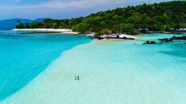 Ziyaretçiler kristal berrak turkuaz suları ve yemyeşil yeşilliklerle çevrili Koh Kham Adası 'nın el değmemiş kıyılarında geziniyorlar. Bu dingin tropikal cennet rahatlama ve keşif için mükemmeldir..