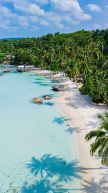 Tayland 'ın Koh Kood Adası' ndaki sakin bir plajın nefes kesici hava manzarasını deneyimleyin. Görkemli turkuaz suları, yemyeşil palmiye ağaçları ve güzel bir manzarayla çevrili.