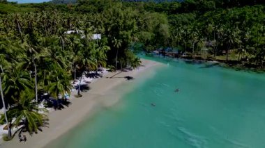 Koh Kood Tayland 'da turkuvaz sularının beyaz kumlarla ve sallanan palmiye ağaçlarıyla buluştuğu el değmemiş bir plajı keşfedin. Ziyaretçiler bu tropikal vahada güneşin altında yüzmeyi ve dinlenmeyi severler..
