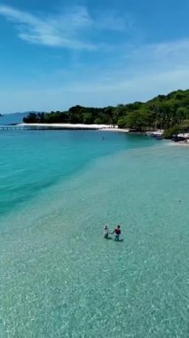 İki birey Koh Kham Adası 'nın huzurlu çevresinin tadını çıkararak Koh Mak' ın berrak sularında yürüyor. Yeşillik ve el değmemiş bir plaj Tayland 'da mükemmel bir tropikal kaçış sağlar.