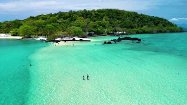 Muhteşem Koh Kham Adası Tayland 'ı keşfedin, kristal berrak turkuaz suların el değmemiş beyaz kumsallarla buluştuğu yer. Ziyaretçiler güneşlenmeyi, yüzmeyi ve nefes kesici manzaraları izlemeyi severler..