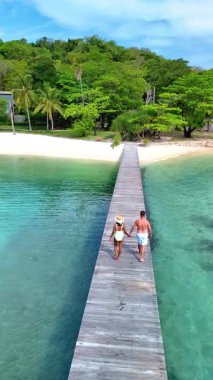 Koh Kham Adası Tayland 'da berrak turkuaz sular ve yemyeşil sularla çevrili sakin bir ahşap iskelede el ele yürüyen bir çift. Romantik bir kaçamak için mükemmel bir gün..