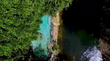 Tayland 'ın yemyeşil yaprakları ve sakin sularıyla çevrili tenha bir vahada gezginler rahatlar. Yağmur ormanlarında yüzme havuzunda bir çiftin İHA görüntüsü