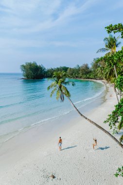 Ziyaretçiler Koh Kood Adası Tayland 'ın el değmemiş kumlu sahillerinde geziyorlar, ılık güneşin ve yumuşak dalgaların tadını çıkarıyorlar..