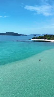 Yeşillik, Tayland 'daki Koh Kham Adası' nda el değmemiş plajlarla buluşuyor. Sakin turkuaz sular, insanlar güneşin altında huzurlu bir günün tadını çıkarırken rahatlamaya davet ediyor. Doğa aşıkları için ideal..