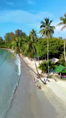 Koh Kood Adası 'nda sakin bir öğleden sonranın tadını çıkar. Yumuşak dalgalar kıyıya vurur, palmiye ağaçları usulca sallanır ve insanlar Tayland' da açık mavi gökyüzünün altında plajda dinlenir.