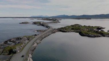 Norveç Atlantik Yolu 'nun dramatik deniz manzaraları ve yemyeşil ile adaları kusursuz bir şekilde birbirine bağlayan güzelliğini deneyimleyin. Gökyüzünü yansıtan sakin suları keşfedin.