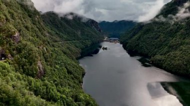Norveç 'te görkemli dağlar ve canlı yeşilliklerle çevrili büyüleyici fiyort manzarasını keşfedin. Sakin sular çarpıcı manzarayı yansıtıyor. Huzurlu bir atmosfer yaratıyor..