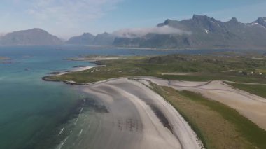 Kamera dramatik kıyı şeritleri ve zümrüt sularının üzerinde süzülürken Lofoten Norveç 'in dingin güzelliğini keşfedin. Bereketli yeşil tepeler ve yüksek tepeler büyüleyici bir manzara yaratır. Güneş ışığıyla yıkanmış..