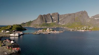 Dramatik dağlar ve sakin sularla çevrili bir Norveç köyünün nefes kesici manzarasını keşfedin. Sakrisoy, Moskenes, Lofoten adaları. Norveç.