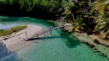 Koh Kood Tayland 'ın sakin sularını ve yemyeşil yeşilliklerini keşfedin kırsal ahşap bir köprüde gezinen iki yolcu gibi. Bu pitoresk yerde doğanın ve maceranın uyumunu deneyimleyin..