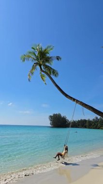 Koh Kood Tayland 'da uzun bir palmiye ağacında sallanan kumlu sahilde huzurlu bir anın tadını çıkar. Sakin mavi sular ve berrak gökyüzü mükemmel bir tropikal kaçış yaratır..