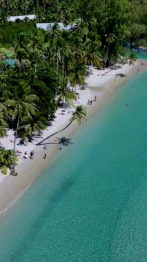 Yumuşak kum, canlı turkuaz sular ve sallanan palmiye ağaçlarıyla Koh Kood Tayland 'da nefes kesici bir plajın huzur verici güzelliğini yaşayın. İnsanlar güneşlenmeyi ve yüzmeyi sever. 