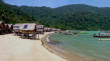 Koh Surin Tayland 'daki sakin bir sahil köyünde dolaşın kumlu bir sahil boyunca hareketsiz kulübeler. Canlı balıkçı tekneleri bereketli yeşilliklerle çevrili berrak sularda sallanır..