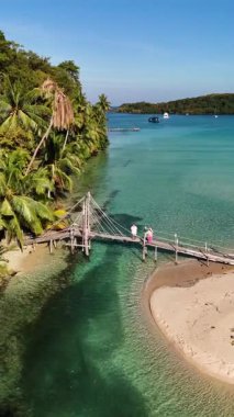 Kristal berrak sular, rüzgarda sallanan gür palmiye ağaçları gibi kumlu sahili kucaklıyor. Tahta bir köprü Koh Kood Tayland 'da cennet gibi bir sahile açılıyor.